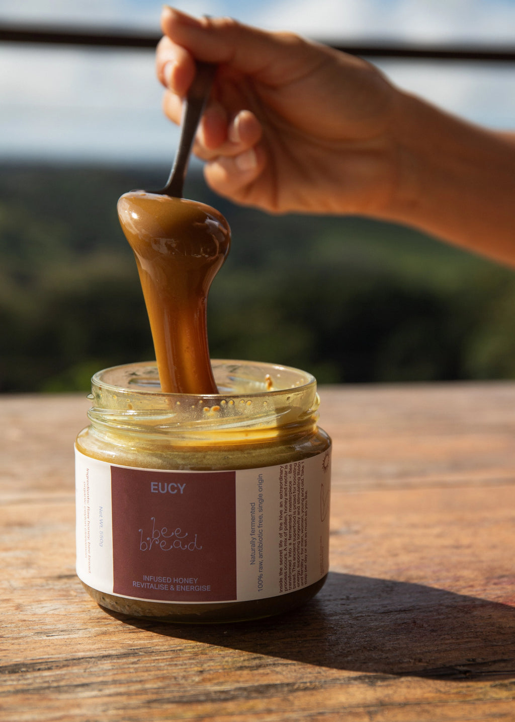 a scoop of eucy australian bee bread being scooped out of the jar, with the bee bread australian honey slowly oozing off the spoon
